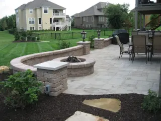 Paver patio with a fire pit, curved seat wall, and flagstone steppers behind a newer two-story home